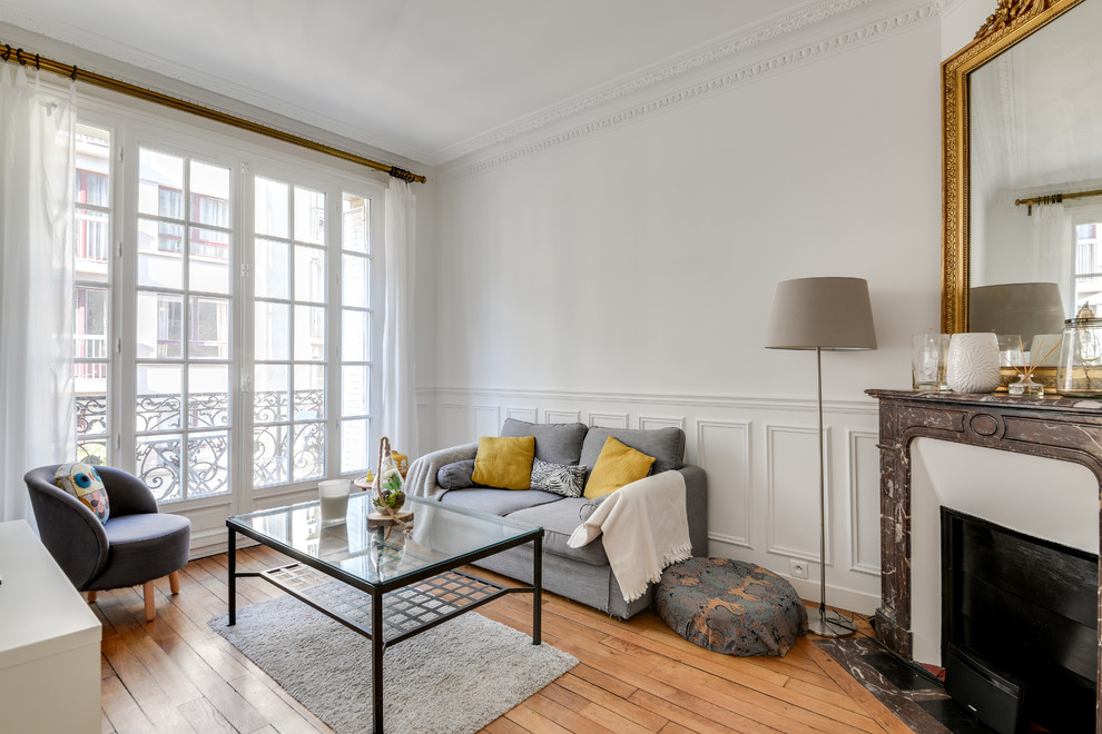 This is an example of a small traditional enclosed living room in Paris with white walls, medium hardwood flooring, a corner fireplace, brown floors and feature lighting.
