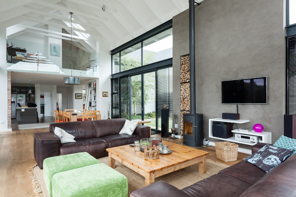Exempel på ett modernt allrum med öppen planlösning, med vita väggar, ljust trägolv, en öppen vedspis, en spiselkrans i metall, en väggmonterad TV och brunt golv