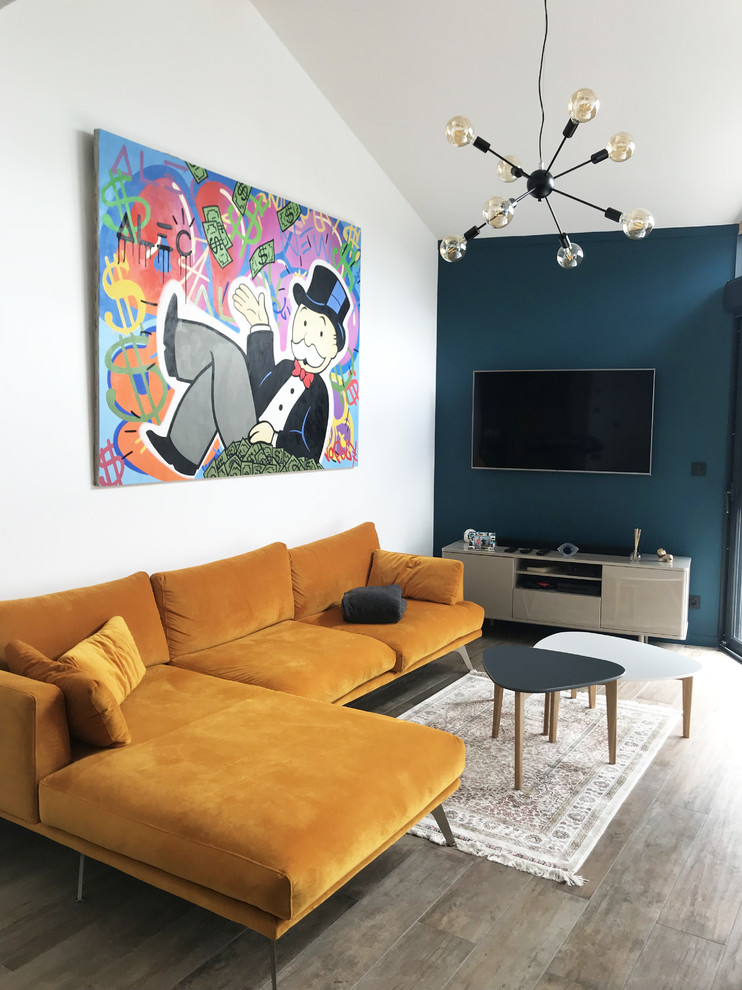 Cette image montre un salon design ouvert avec un mur bleu, tomettes au sol et un téléviseur fixé au mur.