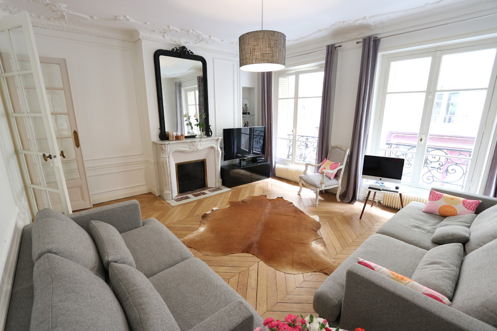 Inspiration pour un salon minimaliste de taille moyenne, ouvert et haussmannien avec un mur blanc, un sol en bois brun, une cheminée standard, un téléviseur indépendant et un sol beige.