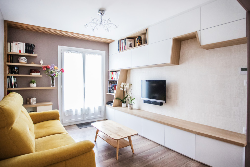 Cette image montre un salon nordique avec un mur beige, sol en stratifié et un téléviseur fixé au mur.