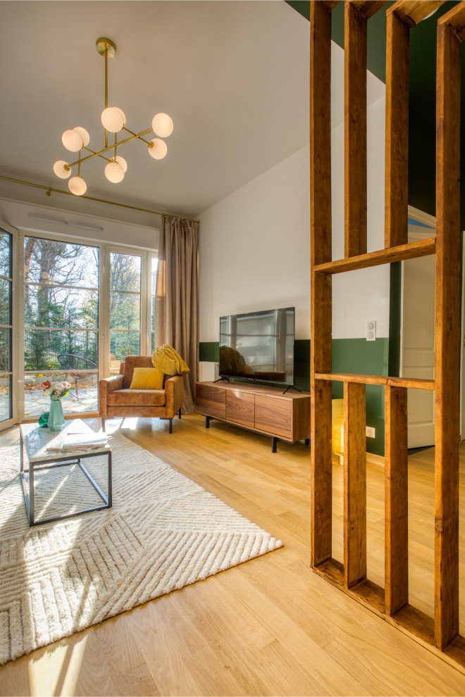 Imagen de salón abierto clásico renovado de tamaño medio con paredes verdes, suelo de madera clara, televisor independiente y suelo marrón