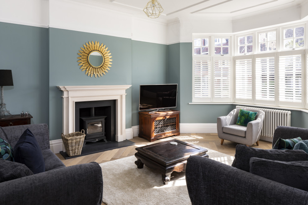Aménagement d'un salon classique fermé avec une cheminée standard, un manteau de cheminée en pierre, un téléviseur indépendant, un sol marron, un mur vert et un sol en bois brun.