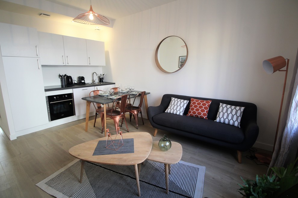 На фото: открытая гостиная комната среднего размера в скандинавском стиле с белыми стенами, светлым паркетным полом, отдельно стоящим телевизором и бежевым полом с