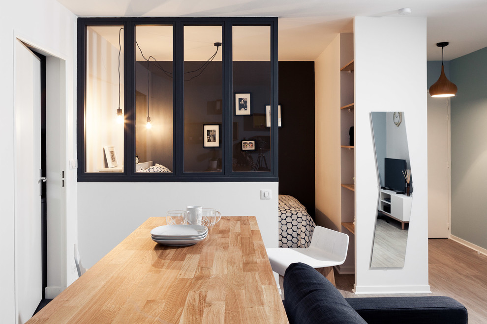 Источник вдохновения для домашнего уюта: маленькая открытая гостиная комната в скандинавском стиле с черными стенами, полом из ламината и отдельно стоящим телевизором для на участке и в саду