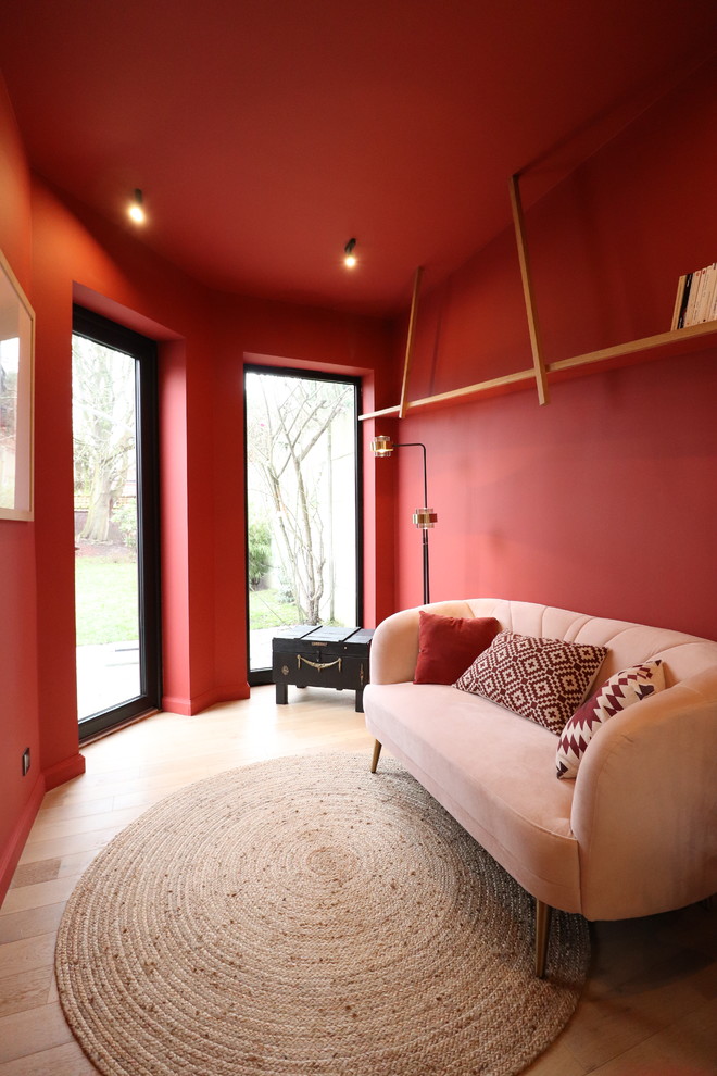 Источник вдохновения для домашнего уюта: открытая гостиная комната среднего размера в современном стиле с с книжными шкафами и полками, красными стенами и светлым паркетным полом без телевизора