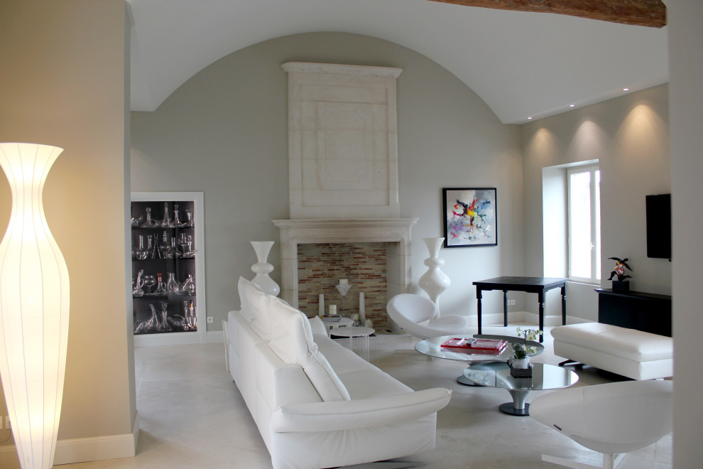 Inspiration pour un très grand salon gris et blanc traditionnel ouvert avec un mur beige, un sol en travertin, une cheminée standard, un manteau de cheminée en pierre, un téléviseur fixé au mur, un sol blanc, un plafond voûté et éclairage.
