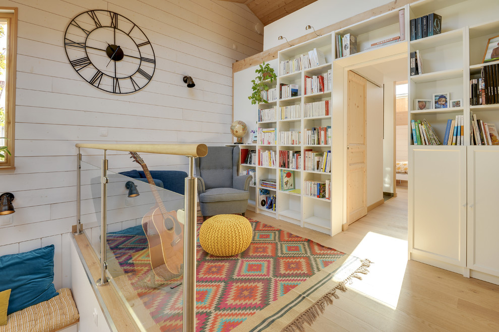 Modelo de biblioteca en casa tipo loft escandinava extra grande sin chimenea y televisor con paredes blancas, suelo de madera clara y suelo beige