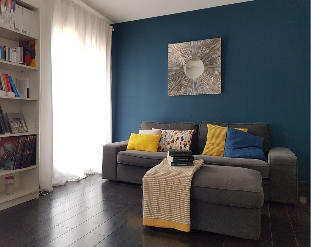 Foto på ett mellanstort skandinaviskt allrum med öppen planlösning, med blå väggar, mörkt trägolv, en fristående TV och svart golv