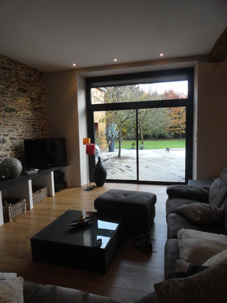 Cette photo montre un grand salon nature ouvert avec un mur gris, parquet clair, une cheminée standard et un téléviseur indépendant.