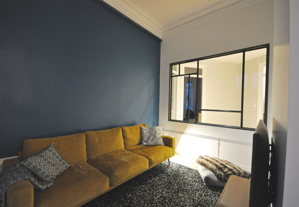 На фото: открытая гостиная комната среднего размера в современном стиле с телевизором на стене, светлым паркетным полом, бежевым полом, синими стенами и панелями на стенах с