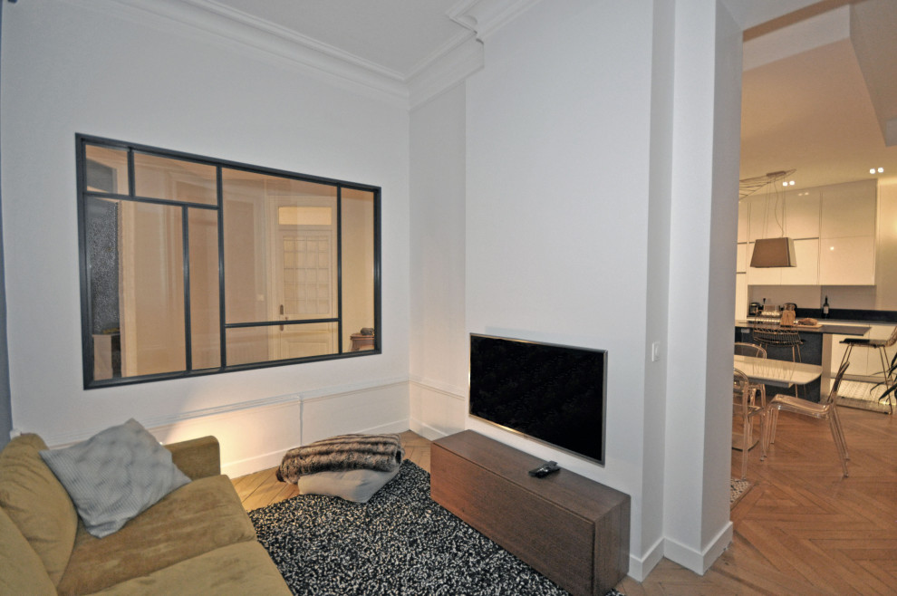 Foto på ett mellanstort funkis allrum med öppen planlösning, med vita väggar, ljust trägolv, beiget golv och en väggmonterad TV