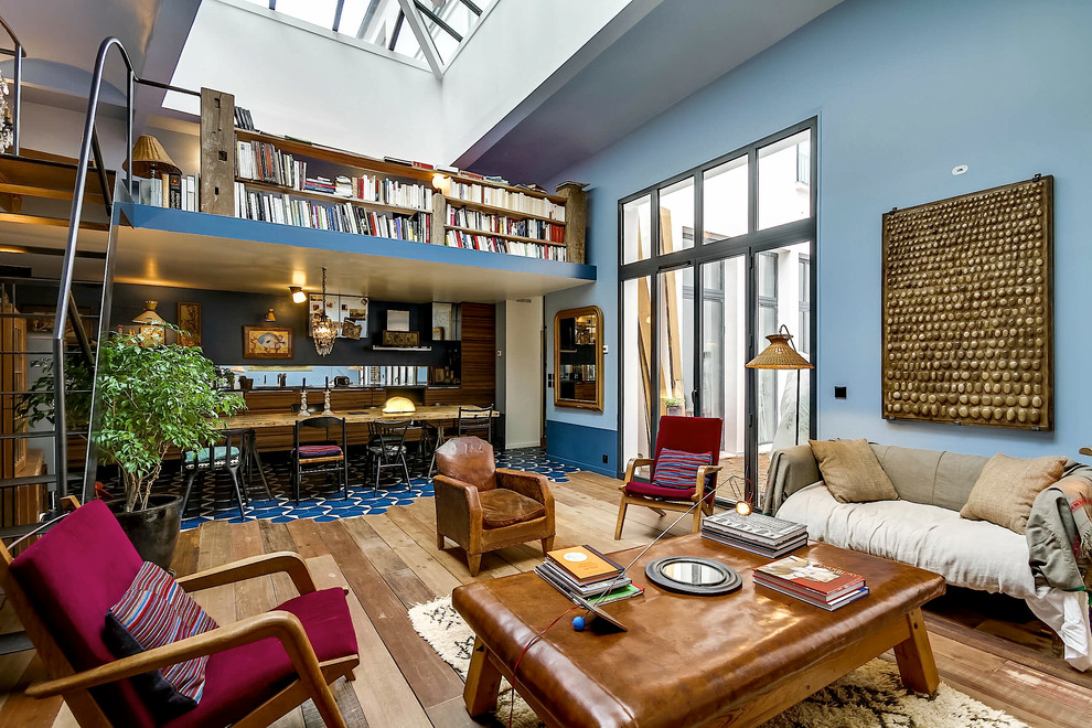 Ispirazione per un grande soggiorno bohémian aperto con pareti blu, pavimento in legno massello medio, libreria, nessun camino e nessuna TV