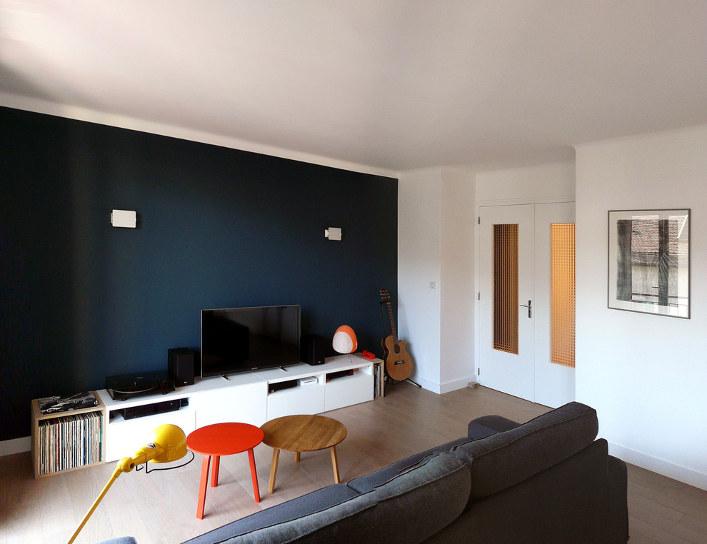 На фото: гостиная комната в стиле модернизм с синими стенами, светлым паркетным полом и отдельно стоящим телевизором с