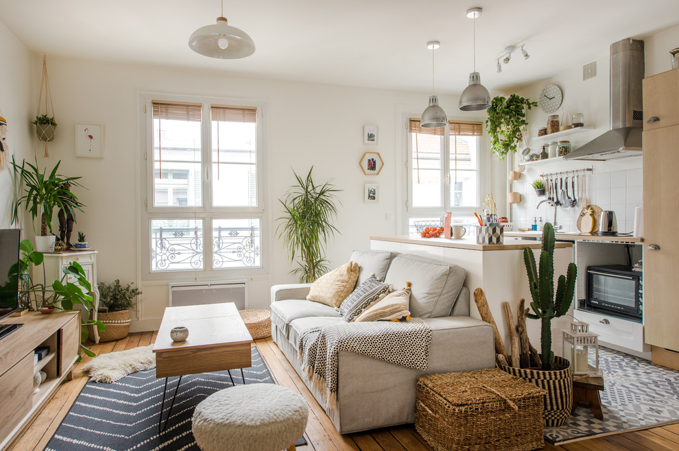 Immagine di un soggiorno scandinavo aperto con pareti bianche, pavimento in legno massello medio, TV autoportante e pavimento marrone