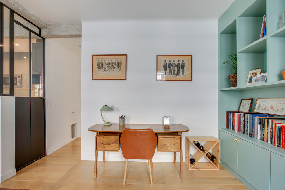 Modelo de biblioteca en casa abierta actual de tamaño medio con paredes blancas, suelo de madera clara y suelo marrón