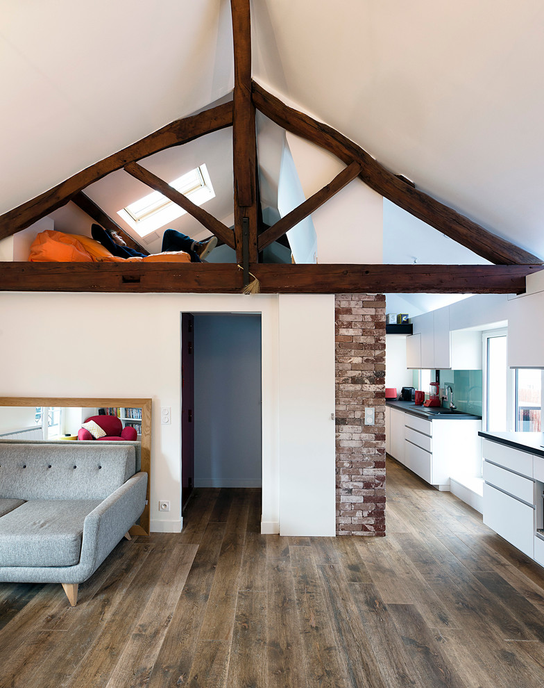 Cette image montre une salle à manger ouverte sur le salon design de taille moyenne avec un mur blanc, un sol en bois brun et une cheminée standard.