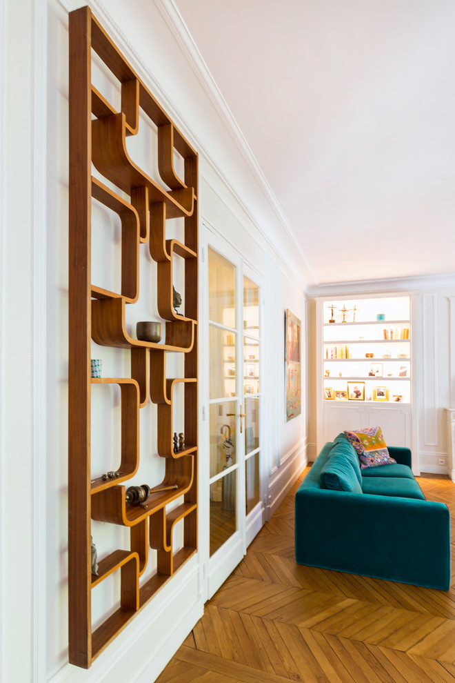 Cette image montre un grand salon design ouvert avec une bibliothèque ou un coin lecture, un mur beige, parquet clair, une cheminée standard, un manteau de cheminée en pierre, aucun téléviseur et un sol marron.