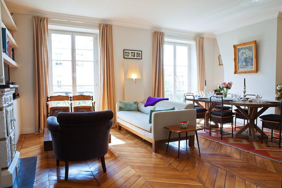 Mittelgroßes, Offenes, Fernseherloses Klassisches Wohnzimmer mit grauer Wandfarbe, Kaminofen, dunklem Holzboden, Kaminumrandung aus Stein und braunem Boden in Paris