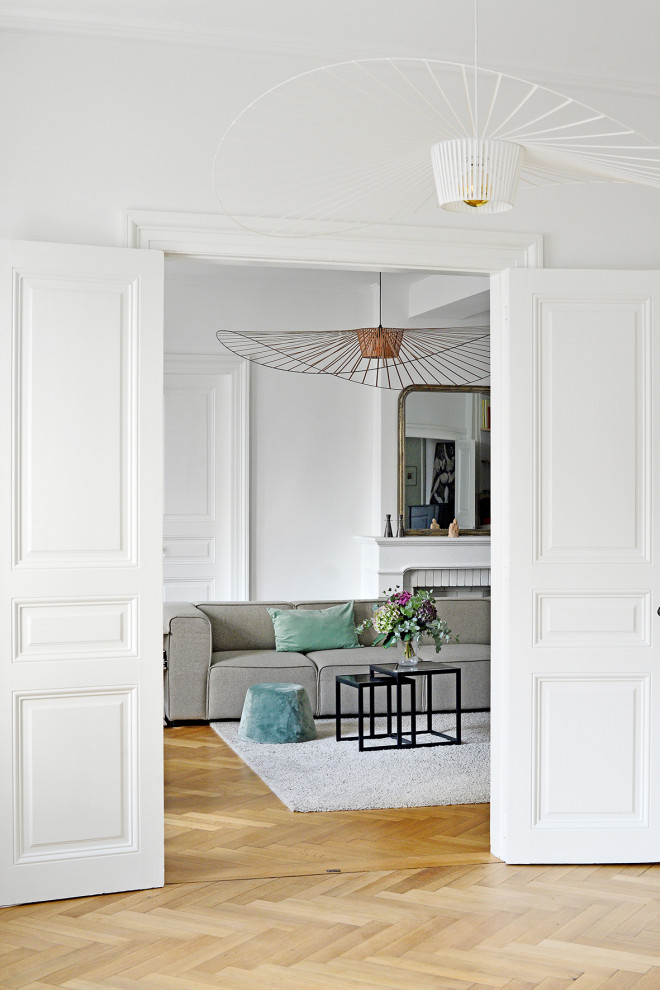 На фото: гостиная комната в стиле модернизм с белыми стенами, светлым паркетным полом, стандартным камином и фасадом камина из камня с