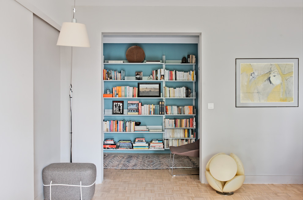 Cette photo montre un petit salon tendance avec une bibliothèque ou un coin lecture et un mur bleu.