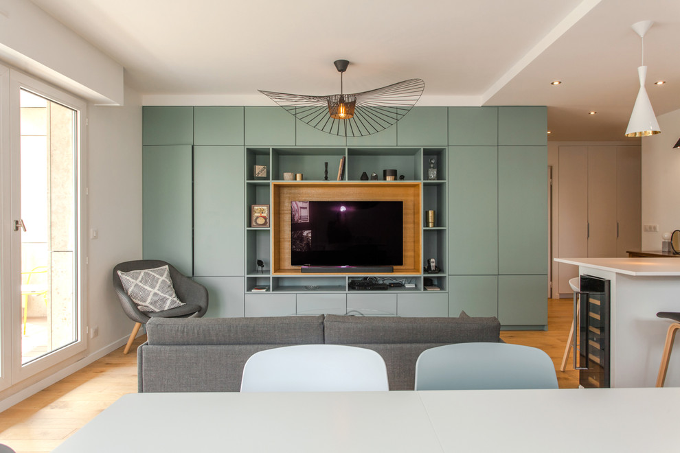 Foto de salón abierto actual sin chimenea con paredes blancas, suelo de madera clara, televisor independiente y suelo beige