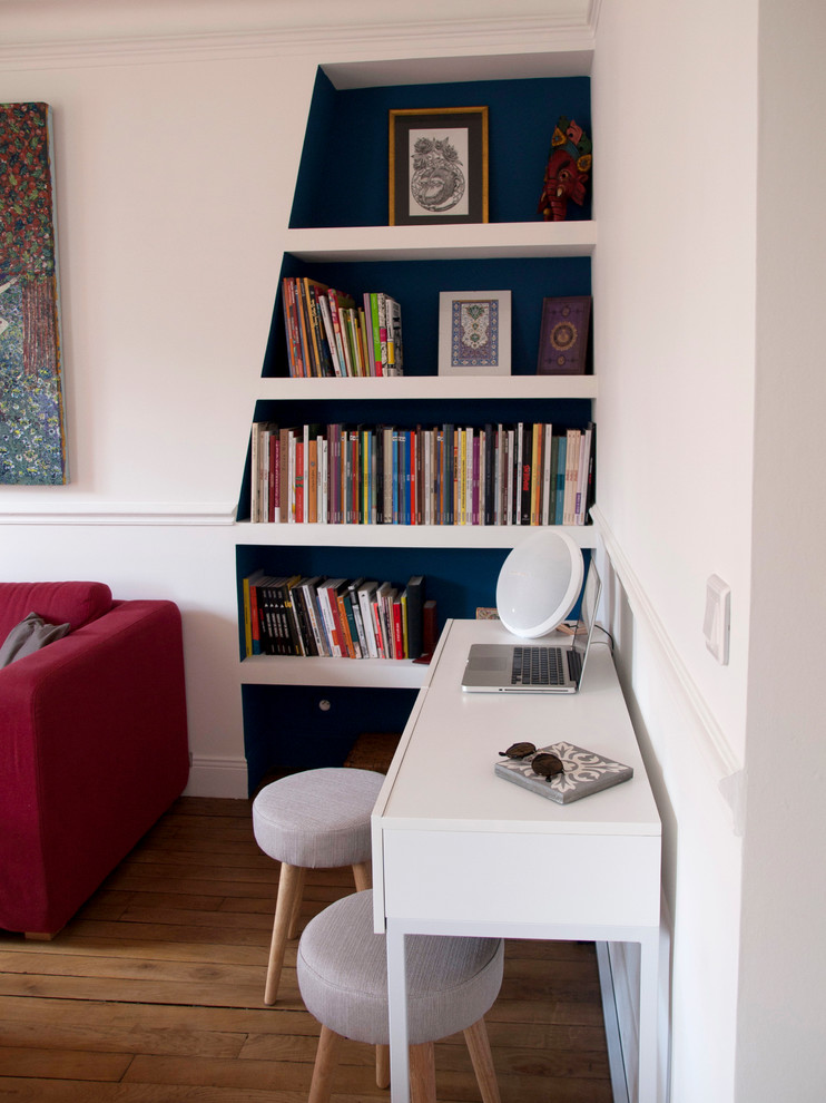 Modern inredning av ett mellanstort separat vardagsrum, med vita väggar, ljust trägolv, en standard öppen spis, ett bibliotek, en spiselkrans i sten och beiget golv