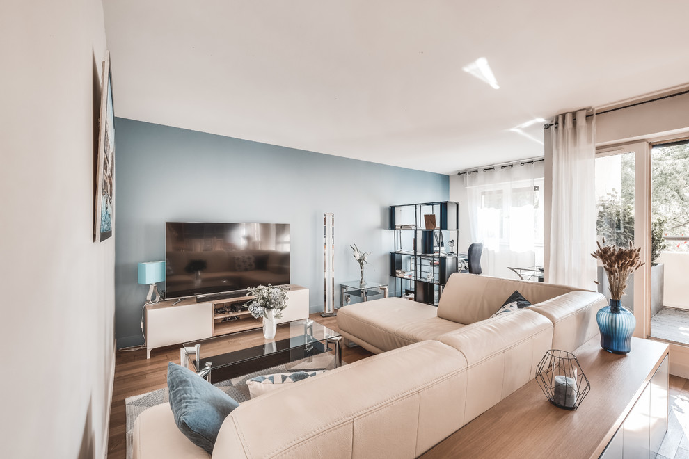 Cette image montre un salon design de taille moyenne et ouvert avec un mur bleu, aucune cheminée, un téléviseur indépendant, un sol marron et un sol en bois brun.