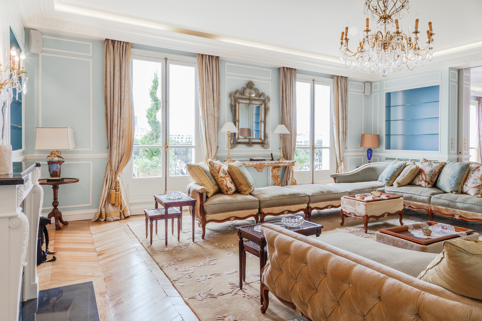 Inspiration for a large traditional formal enclosed living room in Paris with blue walls, light hardwood flooring, a standard fireplace, a stone fireplace surround and no tv.