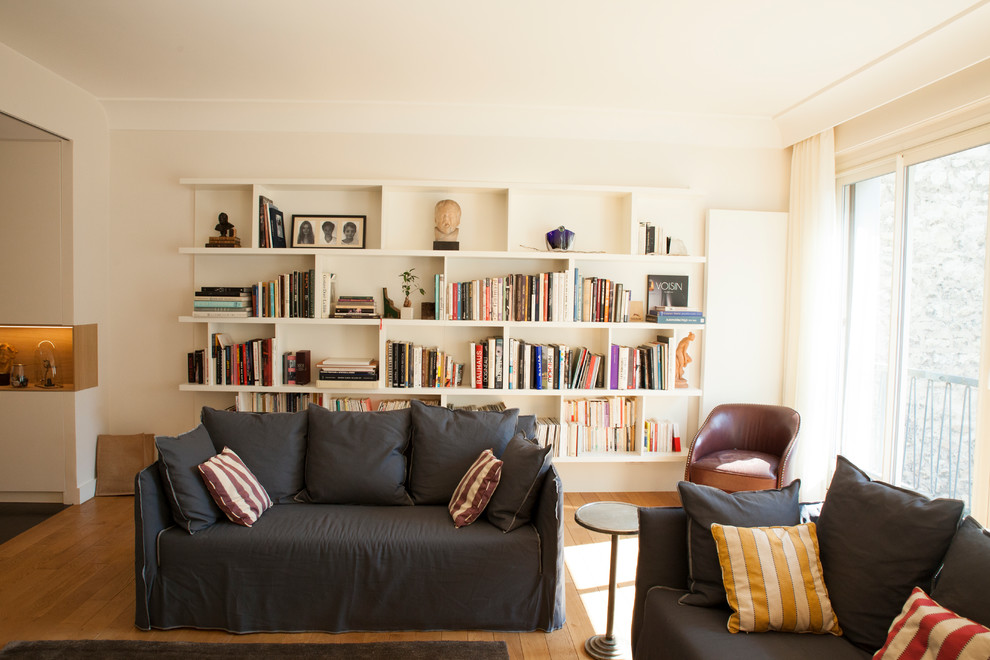 Exemple d'un grand salon tendance ouvert avec une bibliothèque ou un coin lecture, un mur blanc, parquet clair, une cheminée ribbon, un manteau de cheminée en plâtre, un téléviseur dissimulé et un sol marron.