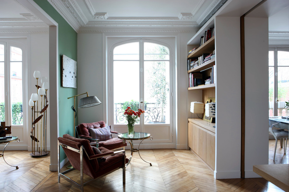 На фото: открытая гостиная комната среднего размера в современном стиле с с книжными шкафами и полками, зелеными стенами и светлым паркетным полом без камина, телевизора с