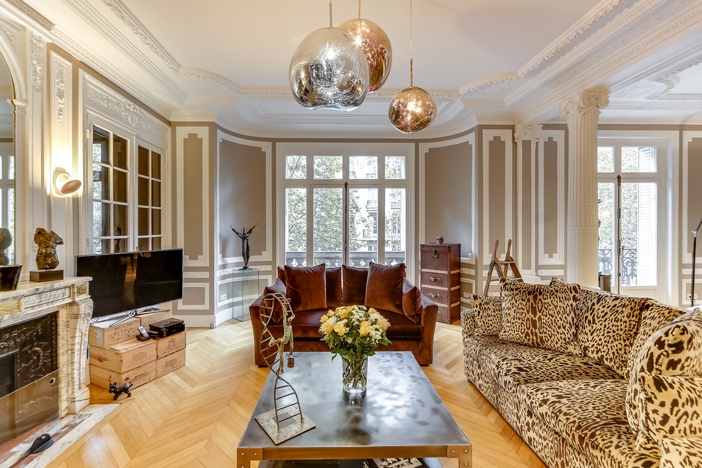 Großes, Offenes Modernes Wohnzimmer mit beiger Wandfarbe, braunem Holzboden, Kamin, Kaminumrandung aus Stein, freistehendem TV und braunem Boden in Paris