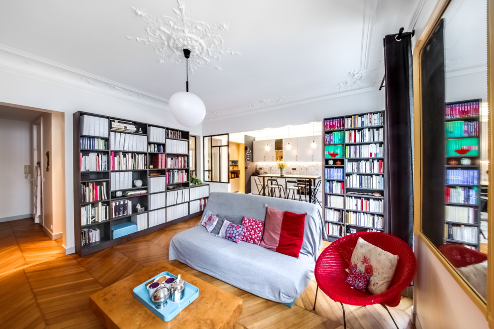 Idée de décoration pour un salon design de taille moyenne et ouvert avec une bibliothèque ou un coin lecture, un mur blanc, parquet clair, aucune cheminée et un téléviseur indépendant.
