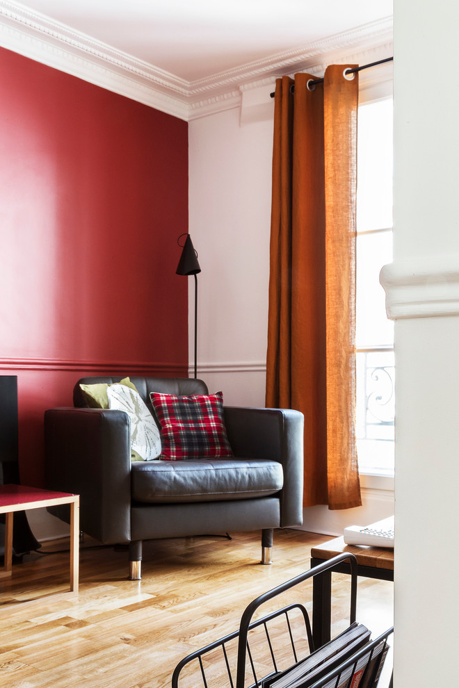 На фото: открытая гостиная комната среднего размера в современном стиле с с книжными шкафами и полками, красными стенами, светлым паркетным полом и телевизором на стене без камина