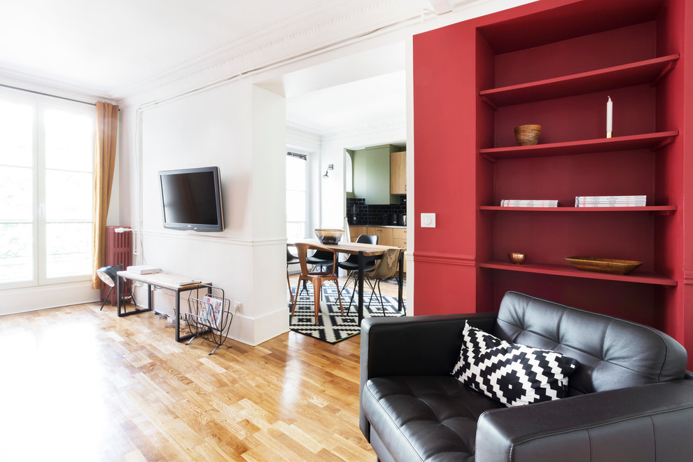 Example of a mid-sized trendy open concept light wood floor living room library design in Paris with red walls, a wall-mounted tv and no fireplace