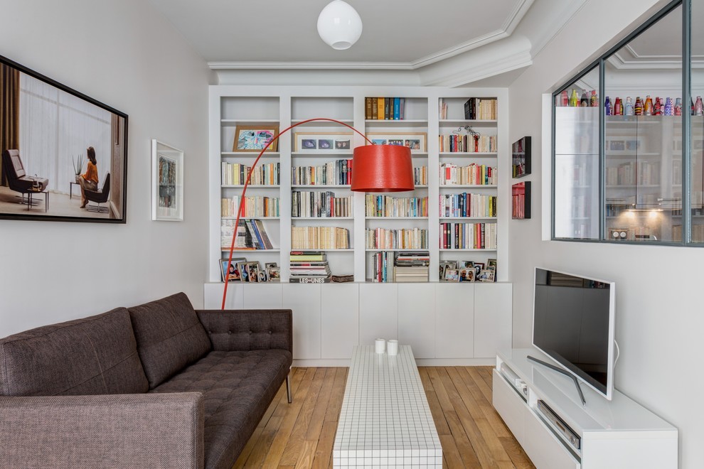 Esempio di un soggiorno minimal di medie dimensioni e chiuso con libreria, pareti bianche, parquet chiaro, nessun camino e TV autoportante