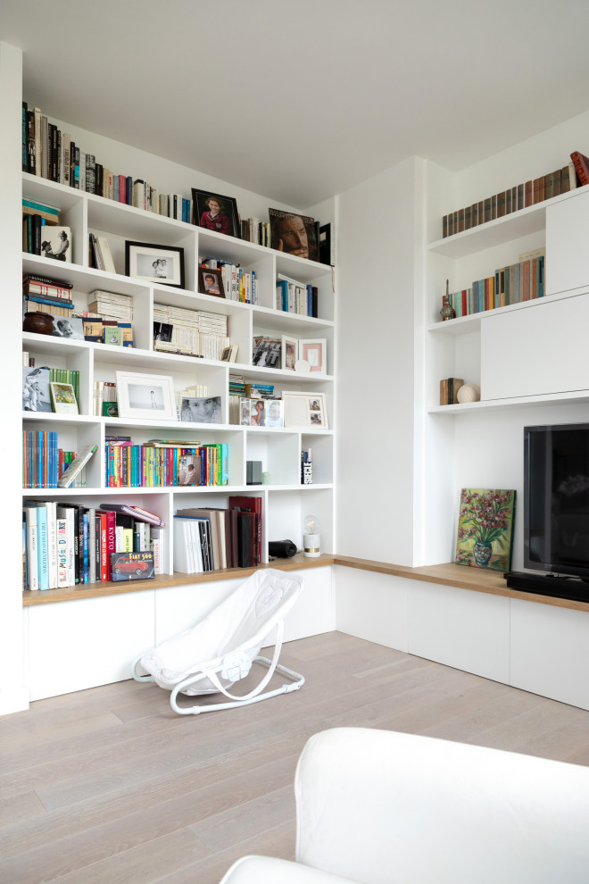 На фото: открытая гостиная комната среднего размера в стиле модернизм с с книжными шкафами и полками, белыми стенами, светлым паркетным полом, отдельно стоящим телевизором и бежевым полом без камина