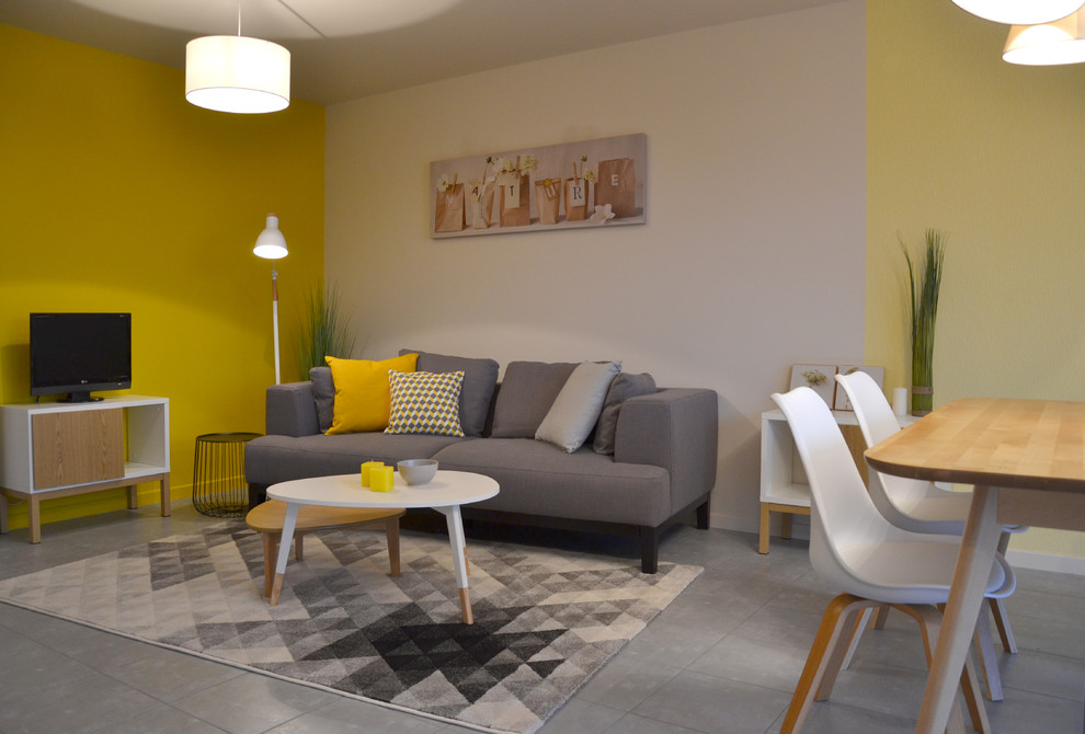 Mittelgroßes, Abgetrenntes Modernes Wohnzimmer ohne Kamin mit gelber Wandfarbe, Keramikboden, freistehendem TV und grauem Boden in Straßburg