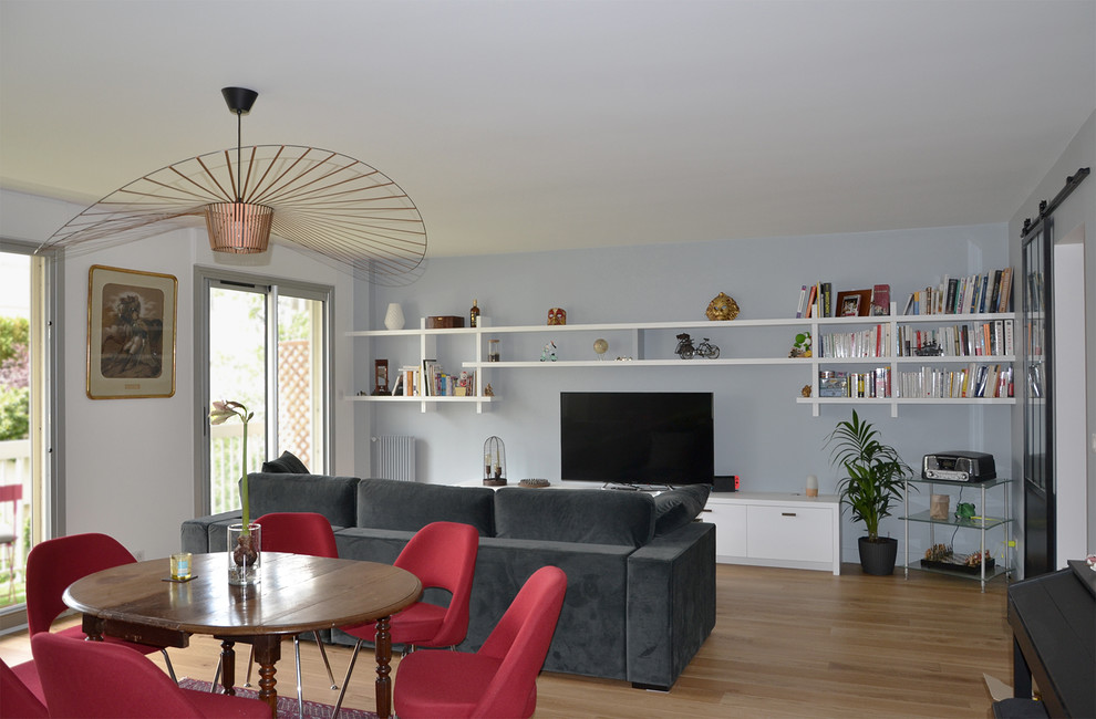 Inspiration pour un salon design avec un mur bleu, parquet clair, aucune cheminée, un téléviseur indépendant et un sol beige.