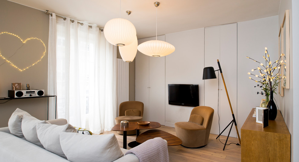 Foto på ett funkis vardagsrum, med grå väggar, mellanmörkt trägolv, en väggmonterad TV och brunt golv