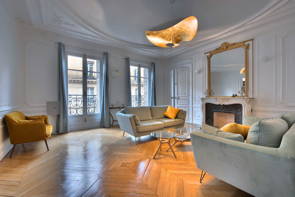 This is an example of a large traditional enclosed living room in Paris with white walls, medium hardwood flooring, a standard fireplace, brown floors, a stone fireplace surround and no tv.