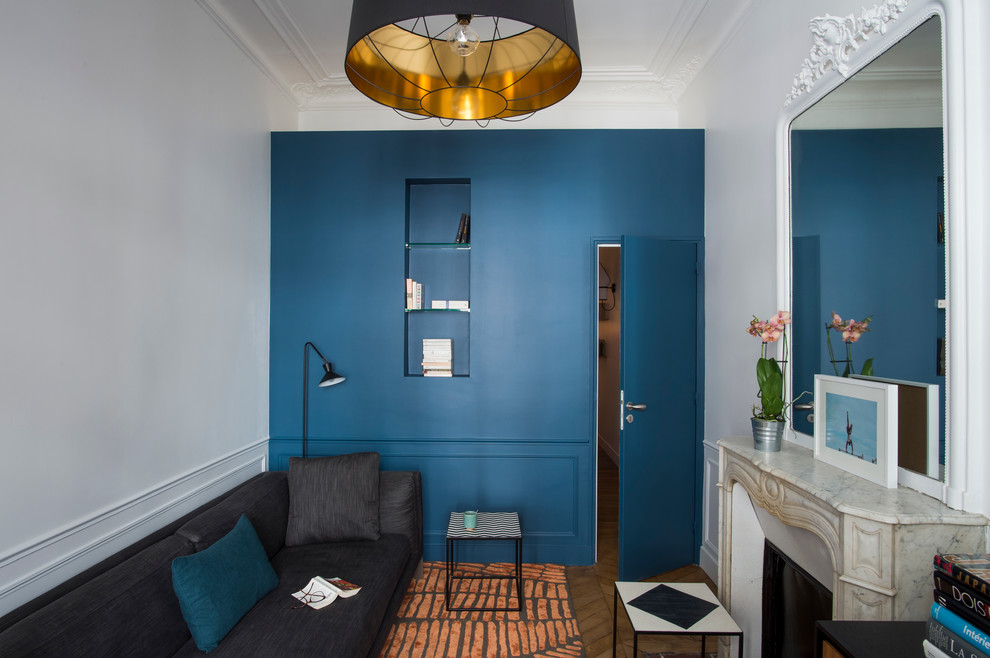 Mittelgroßes, Abgetrenntes Klassisches Wohnzimmer mit blauer Wandfarbe, hellem Holzboden, Kamin, Kaminumrandung aus Stein und beigem Boden in Paris
