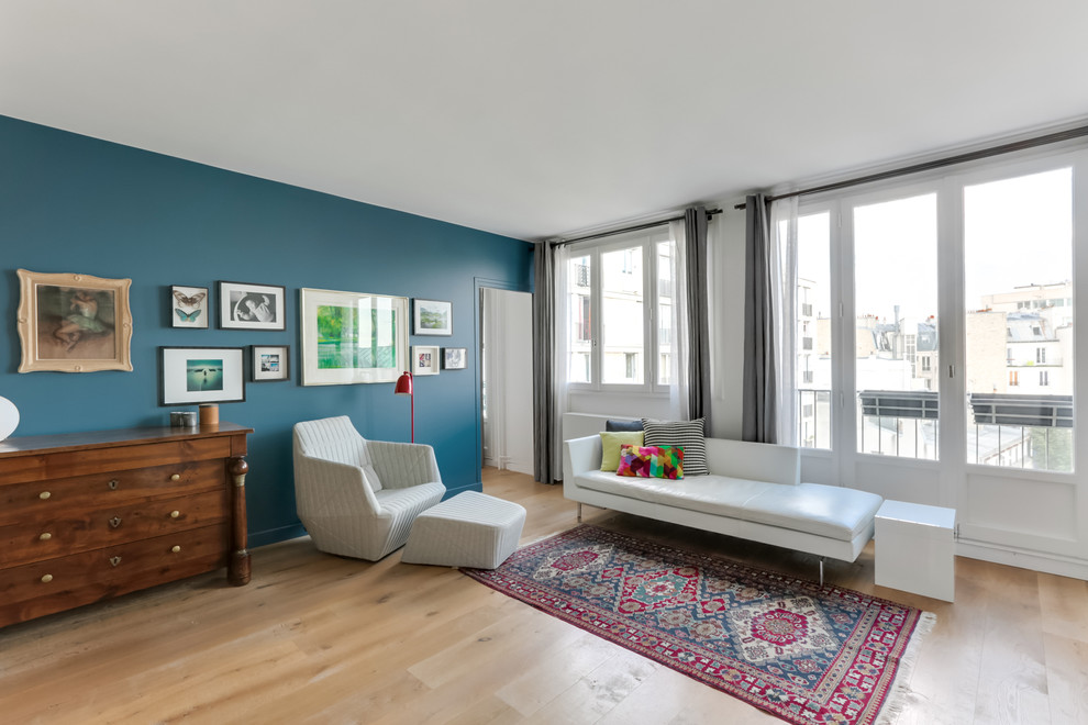 Exemple d'un salon tendance de taille moyenne et ouvert avec un mur bleu, parquet clair, aucune cheminée et un téléviseur fixé au mur.