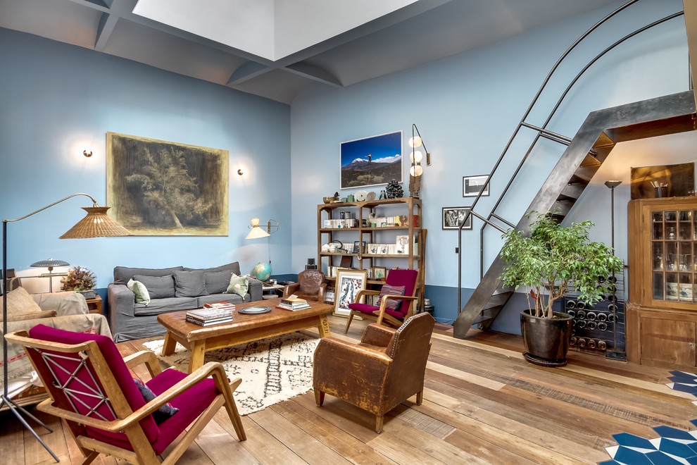Cette photo montre un salon éclectique de taille moyenne et ouvert avec un mur bleu et un sol en bois brun.