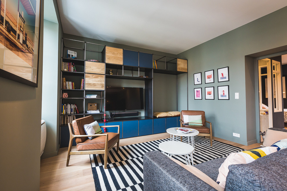 Стильный дизайн: изолированная гостиная комната среднего размера в современном стиле с с книжными шкафами и полками, зелеными стенами, светлым паркетным полом, телевизором на стене и ковром на полу без камина - последний тренд