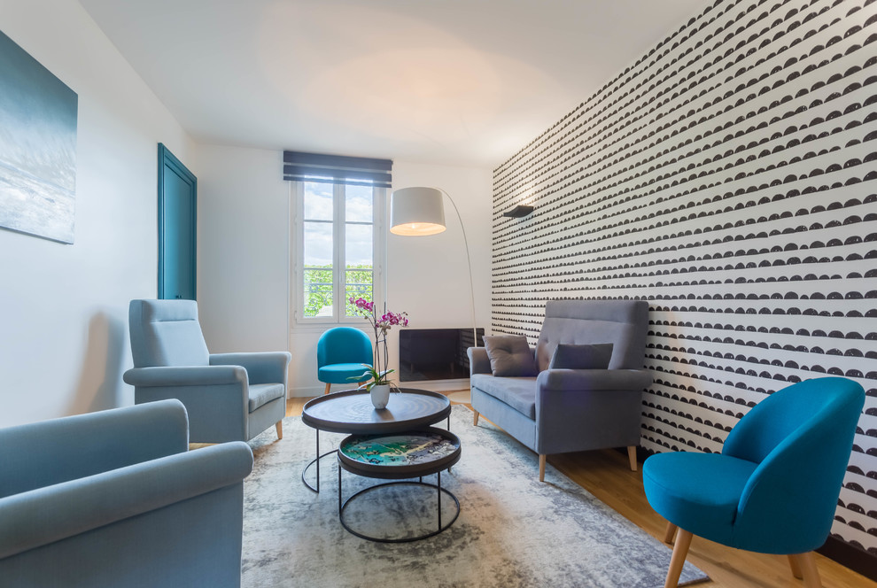 Imagen de salón abierto actual de tamaño medio sin chimenea y televisor con paredes multicolor, suelo de madera clara y suelo beige