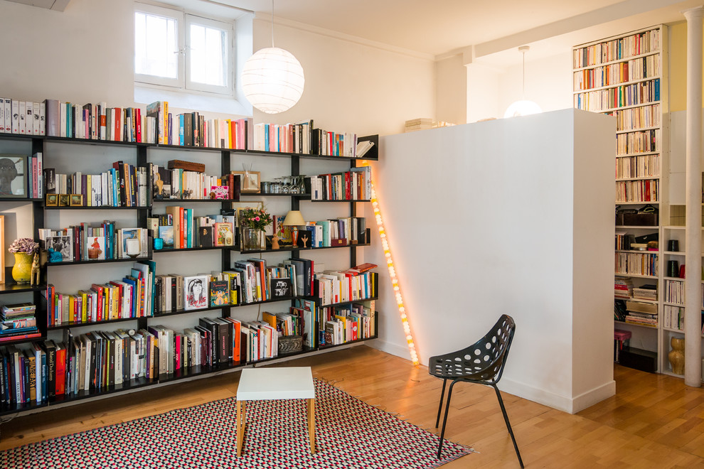 Ispirazione per un soggiorno design di medie dimensioni con libreria, pareti bianche, pavimento in legno massello medio, nessun camino e nessuna TV