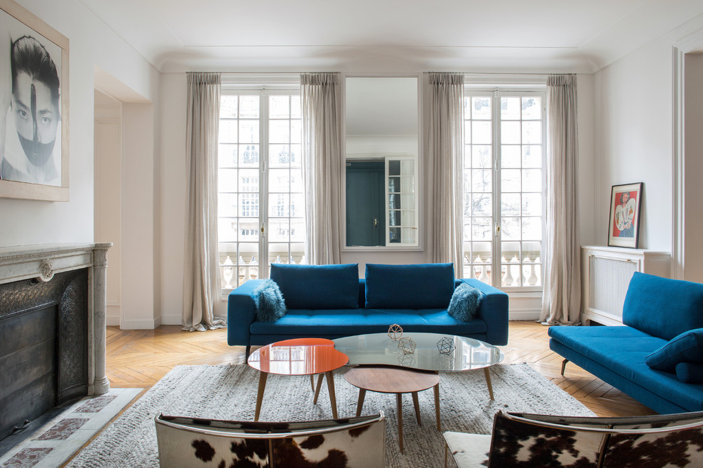 Источник вдохновения для домашнего уюта: большая парадная, изолированная гостиная комната в современном стиле с белыми стенами, паркетным полом среднего тона, стандартным камином, фасадом камина из камня и синим диваном без телевизора