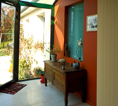 На фото: открытая гостиная комната среднего размера в стиле неоклассика (современная классика) с оранжевыми стенами, темным паркетным полом, двусторонним камином и отдельно стоящим телевизором