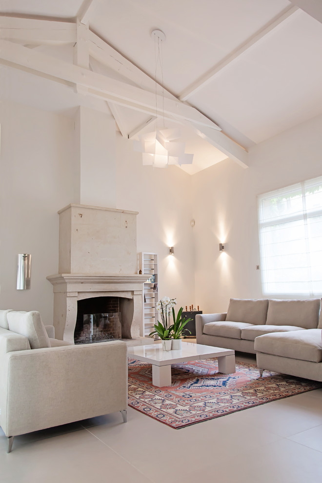 リヨンにある高級な広いトランジショナルスタイルのおしゃれなリビング (白い壁、セラミックタイルの床、標準型暖炉、石材の暖炉まわり、テレビなし) の写真